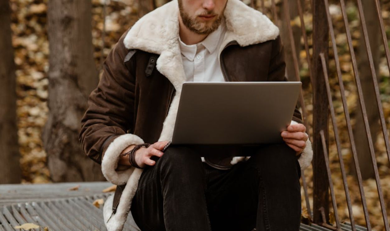 Woman in Brown Coat Sitting on Black Metal Bench
