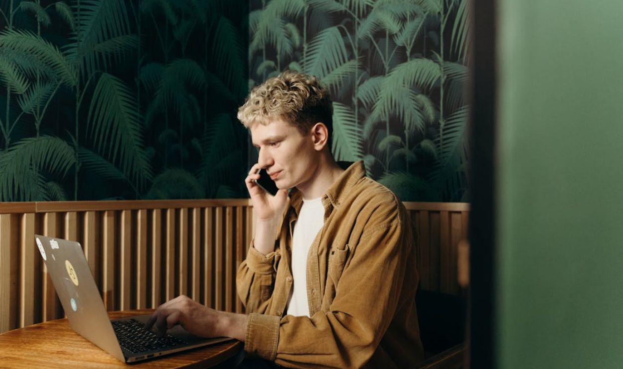 Man in Talking on the Phone While Using a Laptop