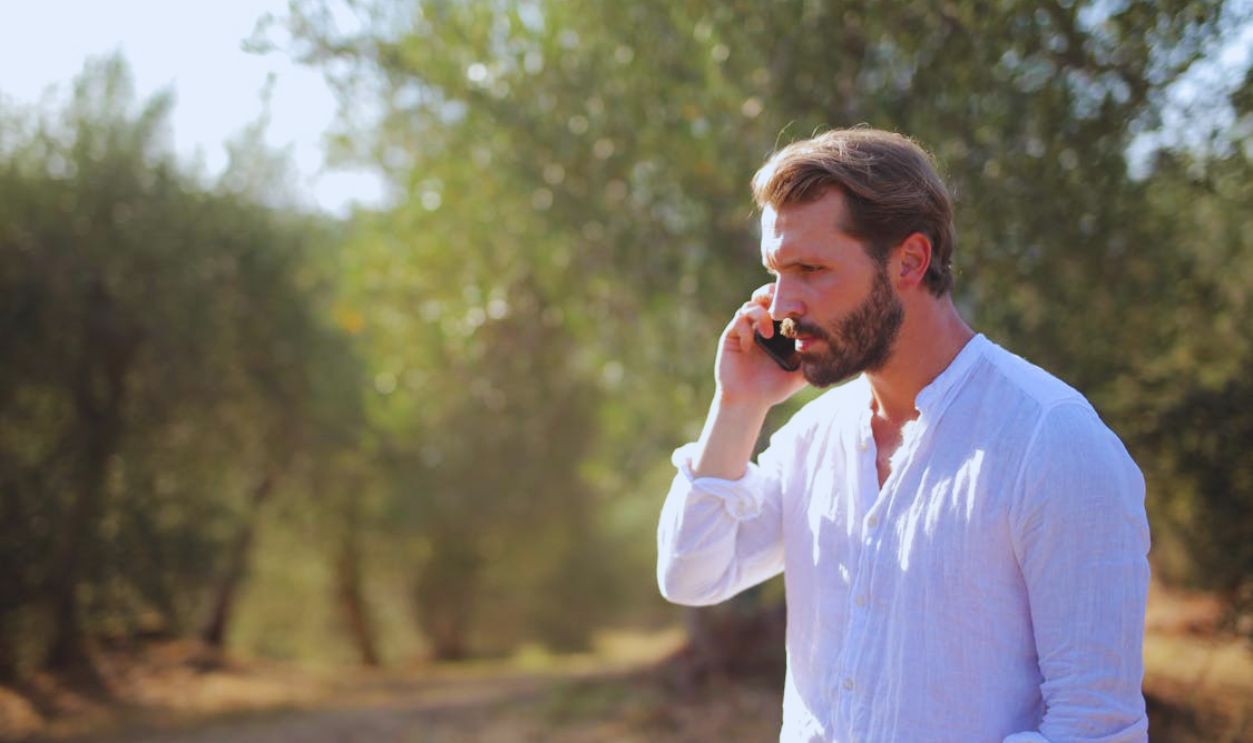 Man in White Long Sleeves Talking on Phone