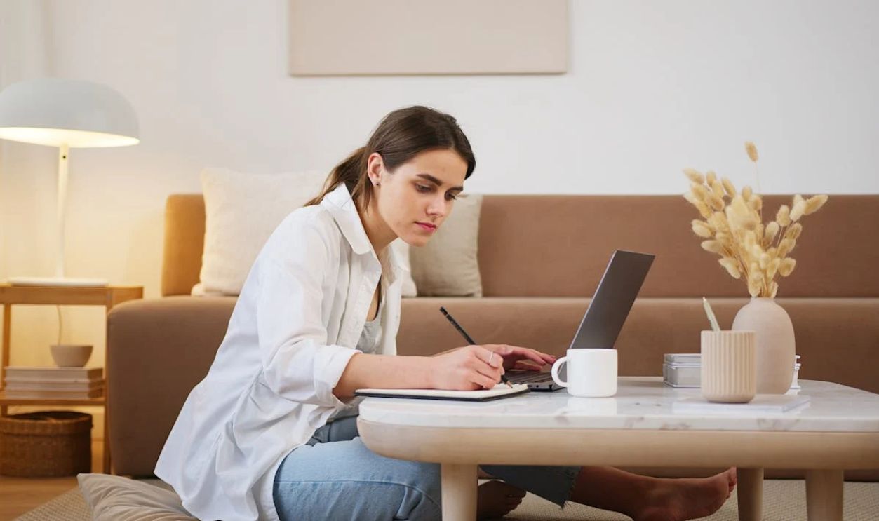 Young woman using laptop and taking notes