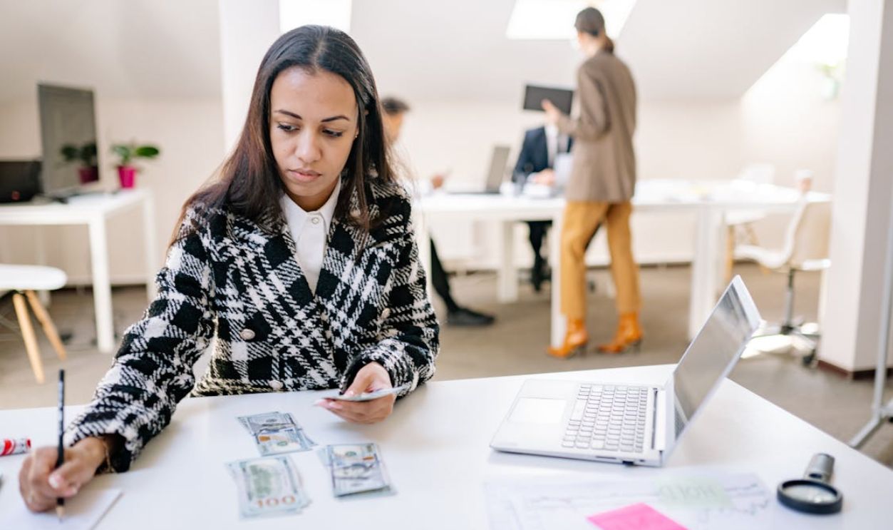 Woman Wearing a Coat Holding Cash and a Pencil