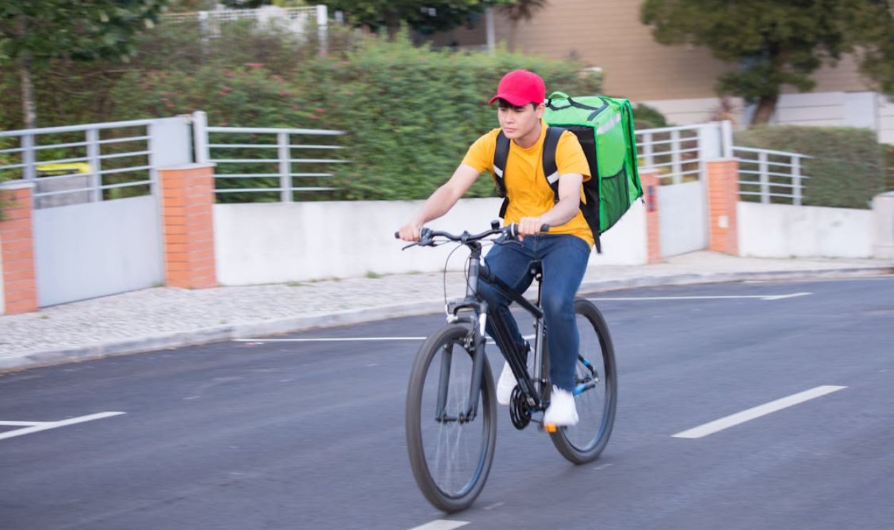 Man in Yellow Shirt Riding a Black Bicycle on Road