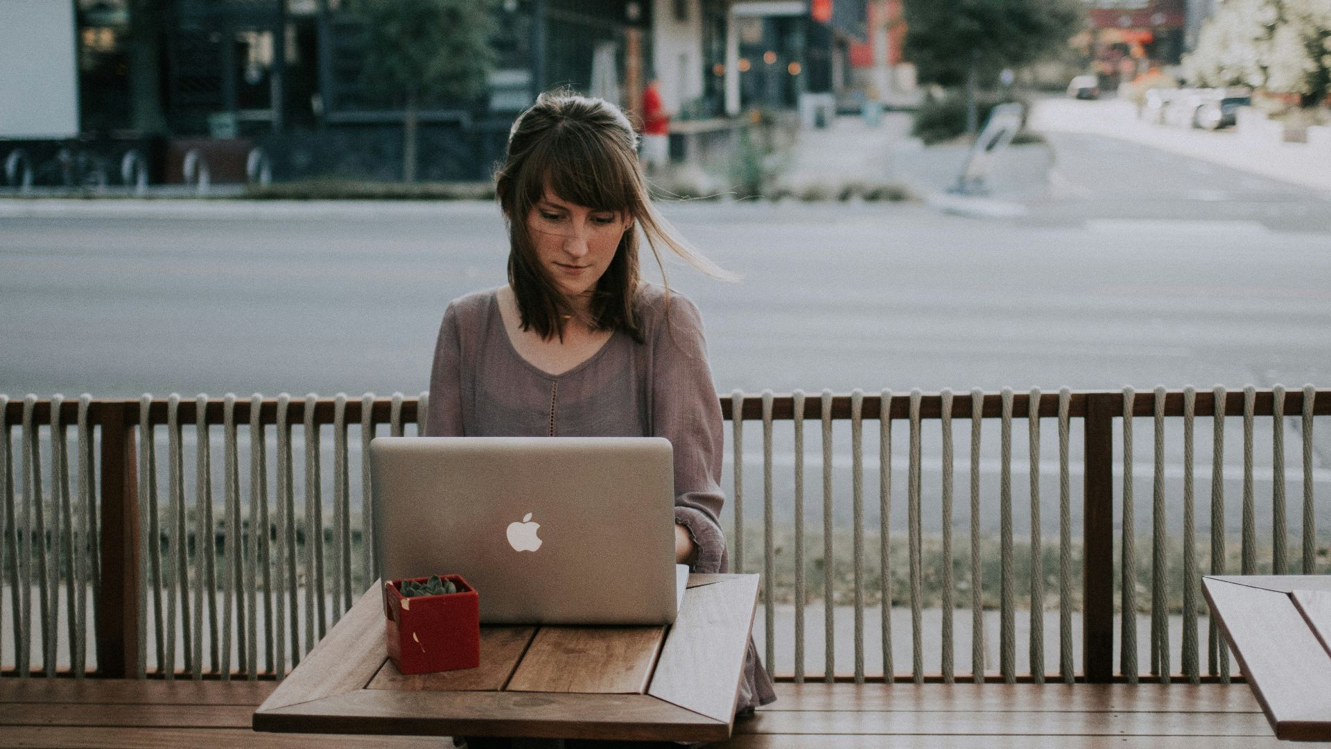 woman in gray shirt sitting on bench in front of MacBook