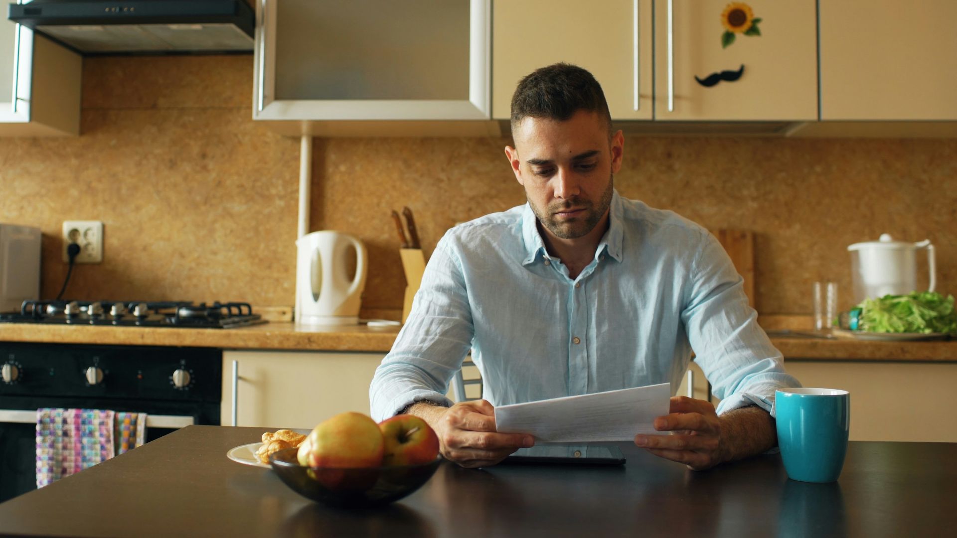 Man reading document at kitchen table with coffee