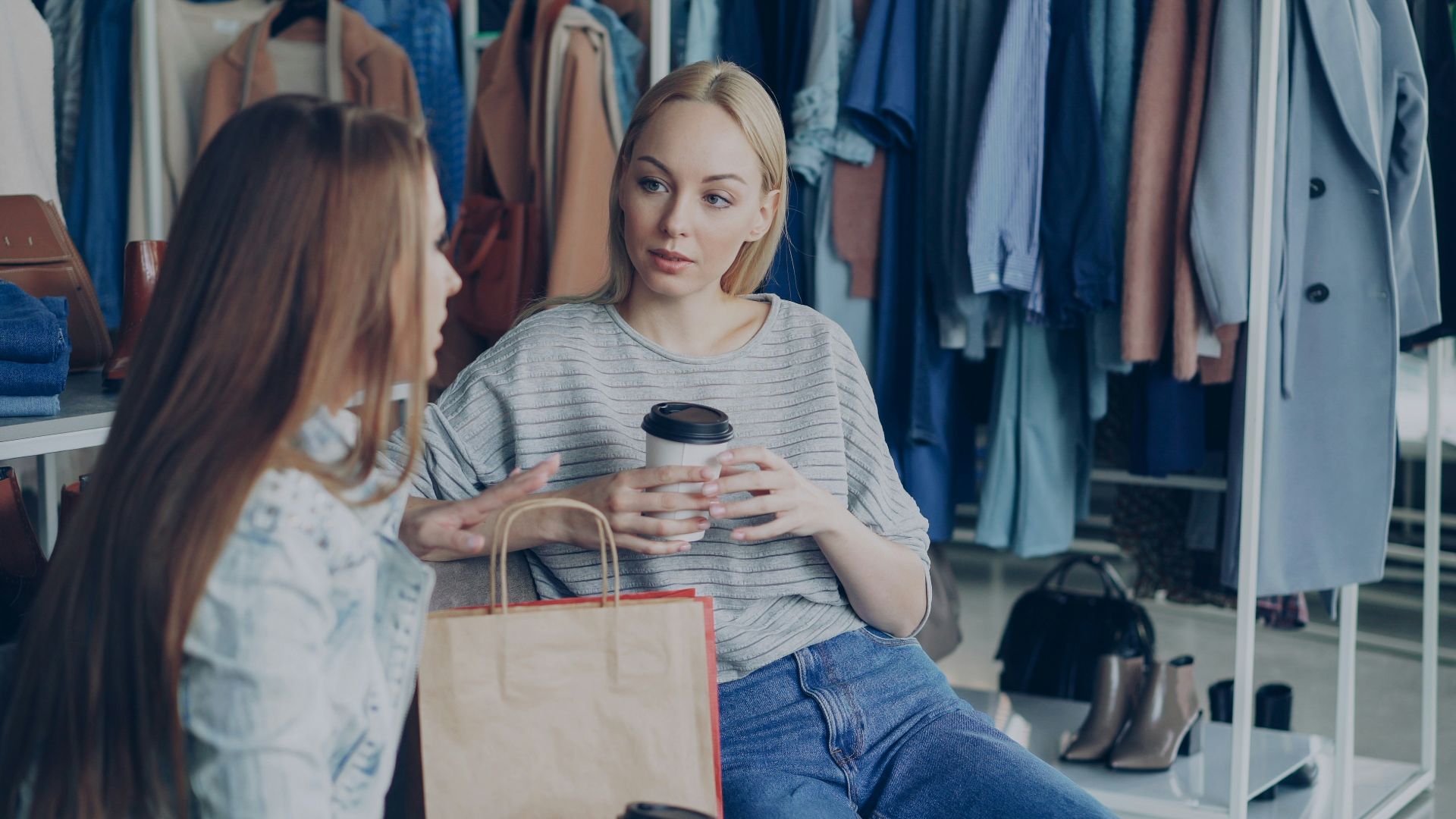Two women chat in a clothing store.