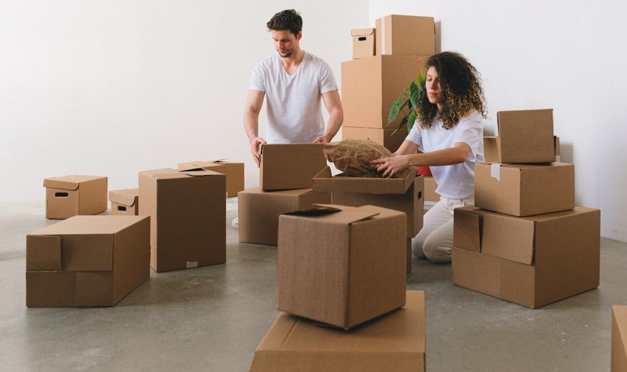 Focused young couple packing carton boxes before relocation