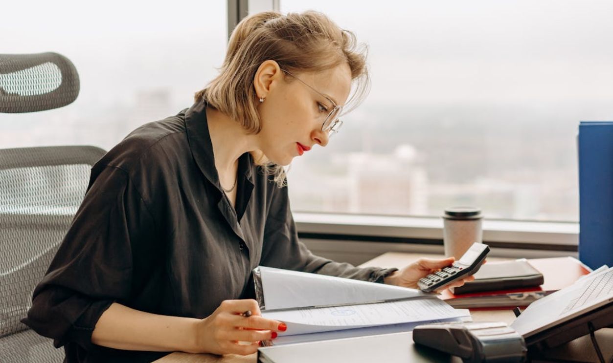 Woman in Polo Long Sleeves Computing Using a Calculator