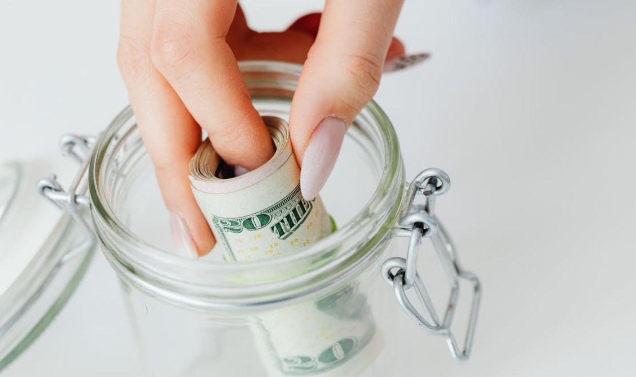 Close-Up Shot of a Person Saving Money in the Glass Jar