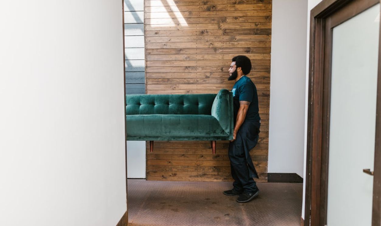 Man in Blue Denim Jeans Sitting on Green Sofa