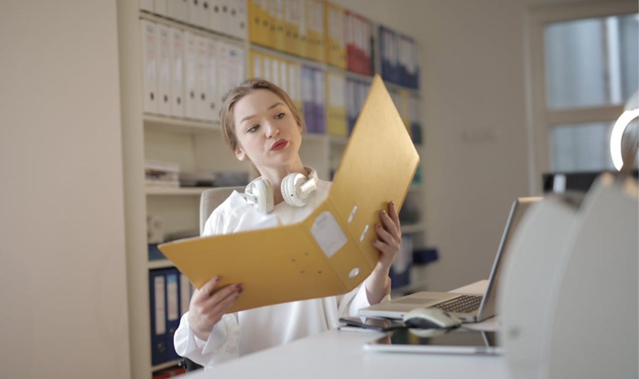 Thoughtful female office worker with folder in workplace