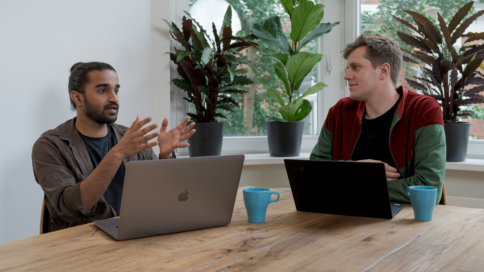 man in red and black crew neck t-shirt using silver macbook