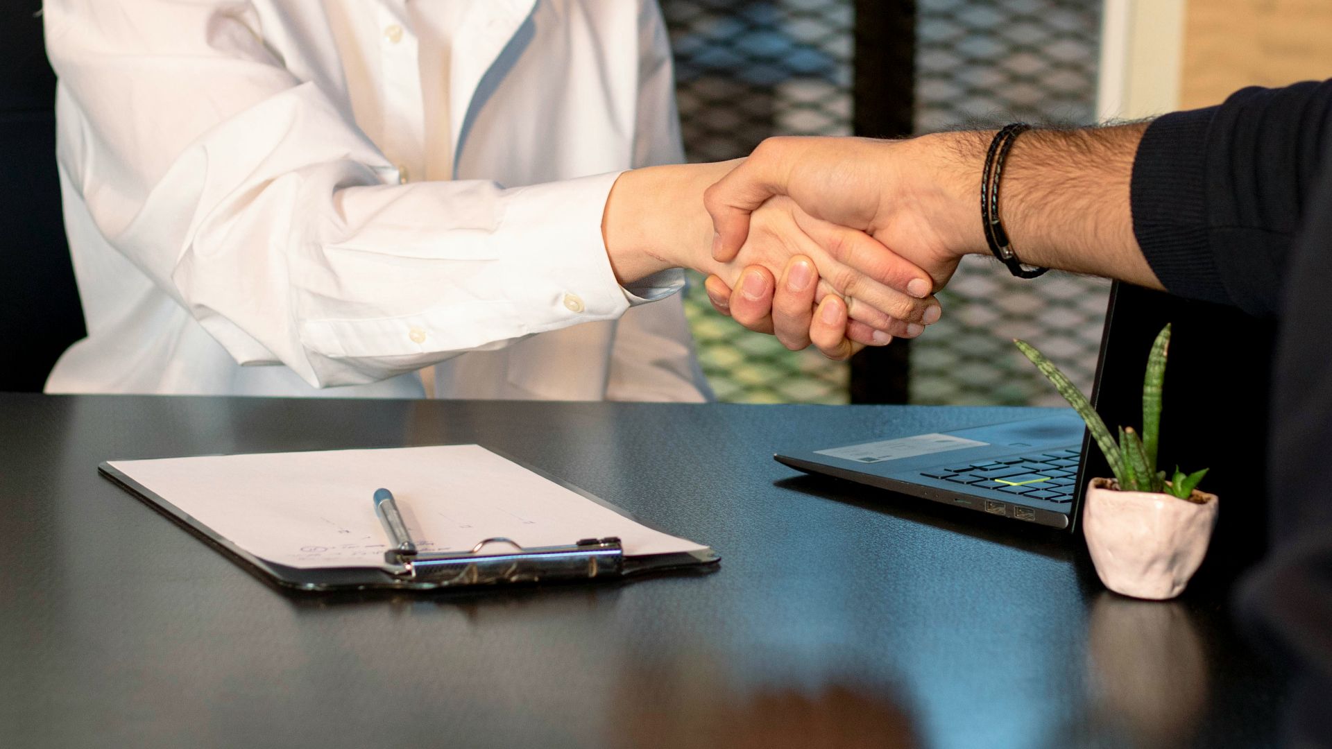 a man and a woman shaking hands in front of a laptop