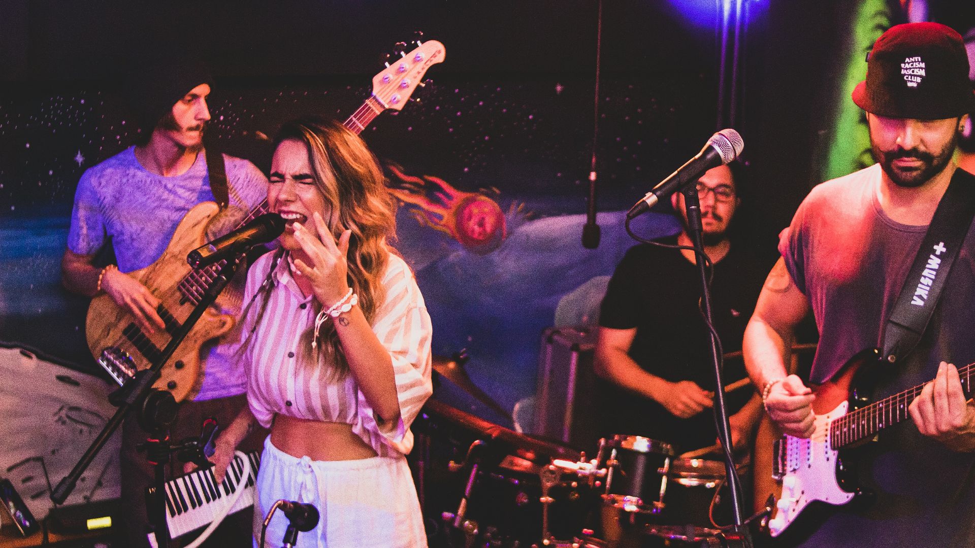 a woman singing into a microphone while playing guitar