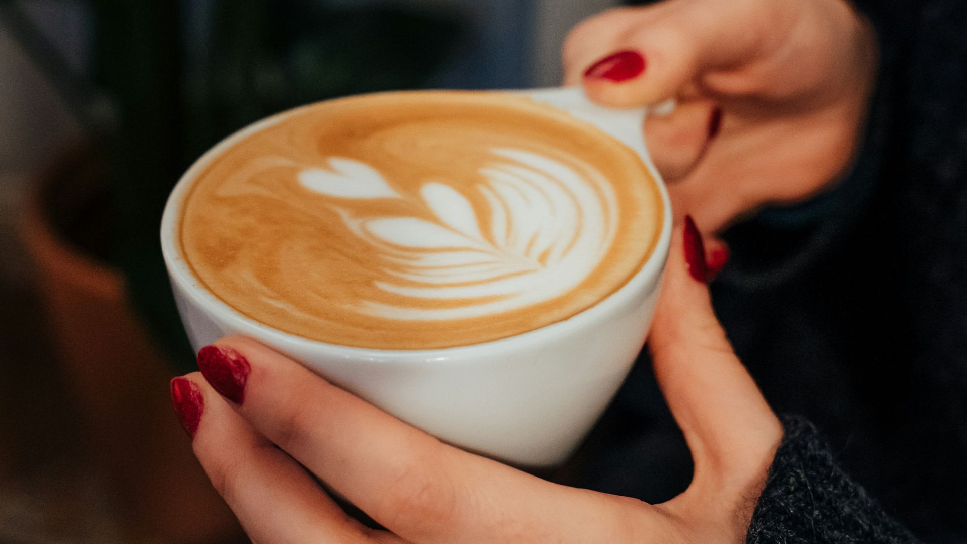 person holding white ceramic cup with brown liquid