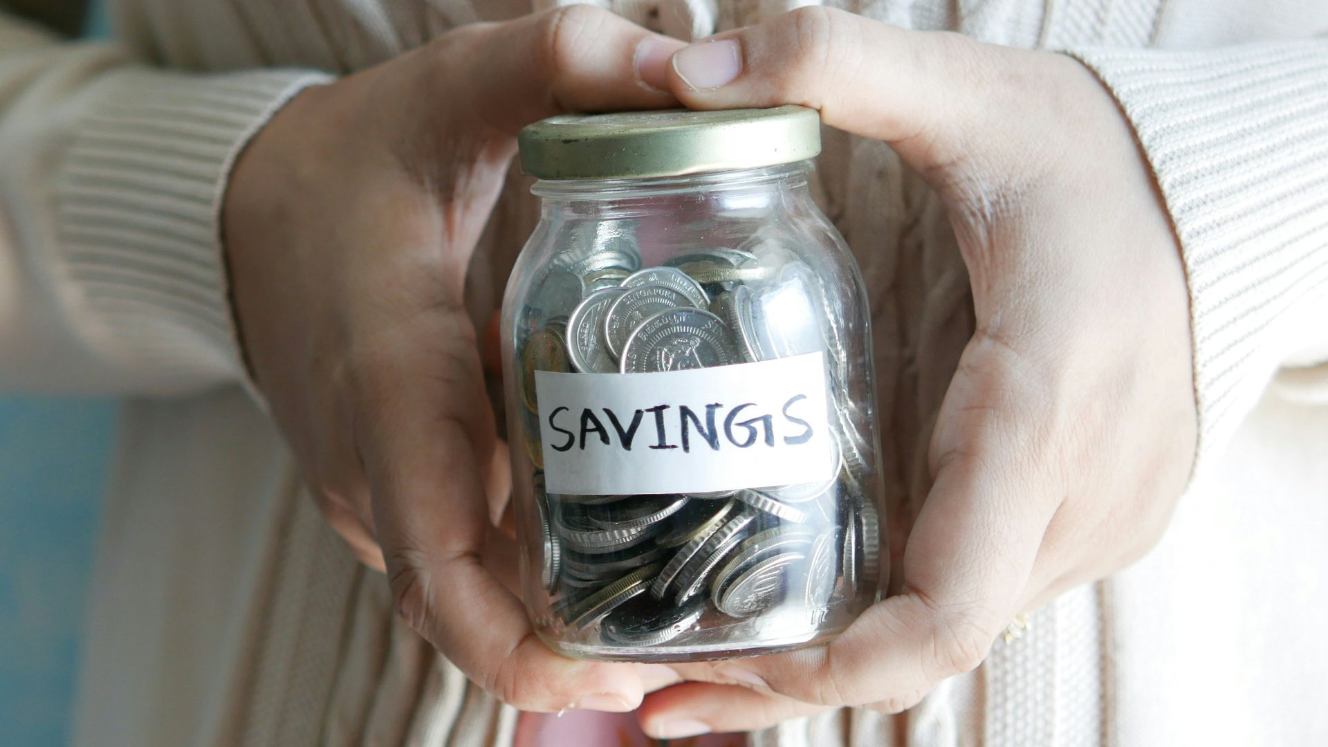 a woman holding a jar with savings written on it