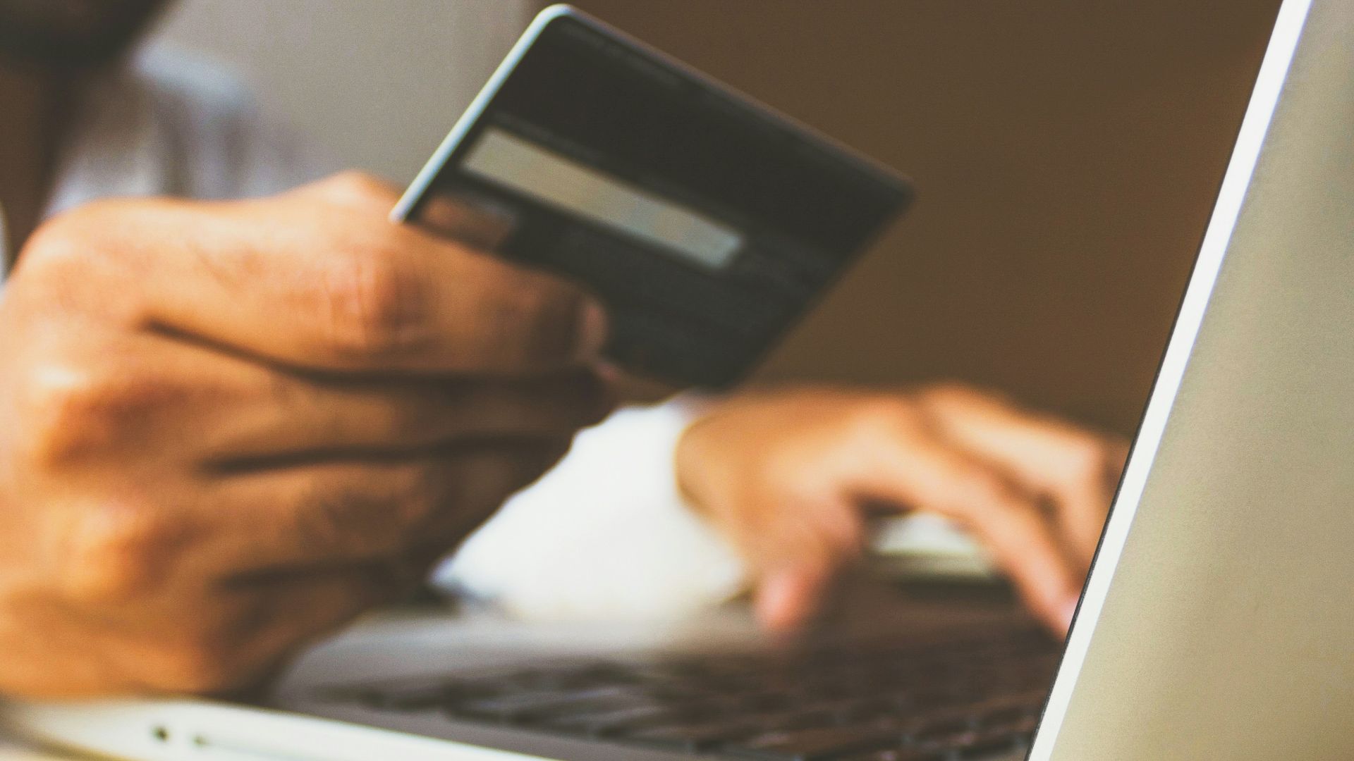 person using laptop computer holding card