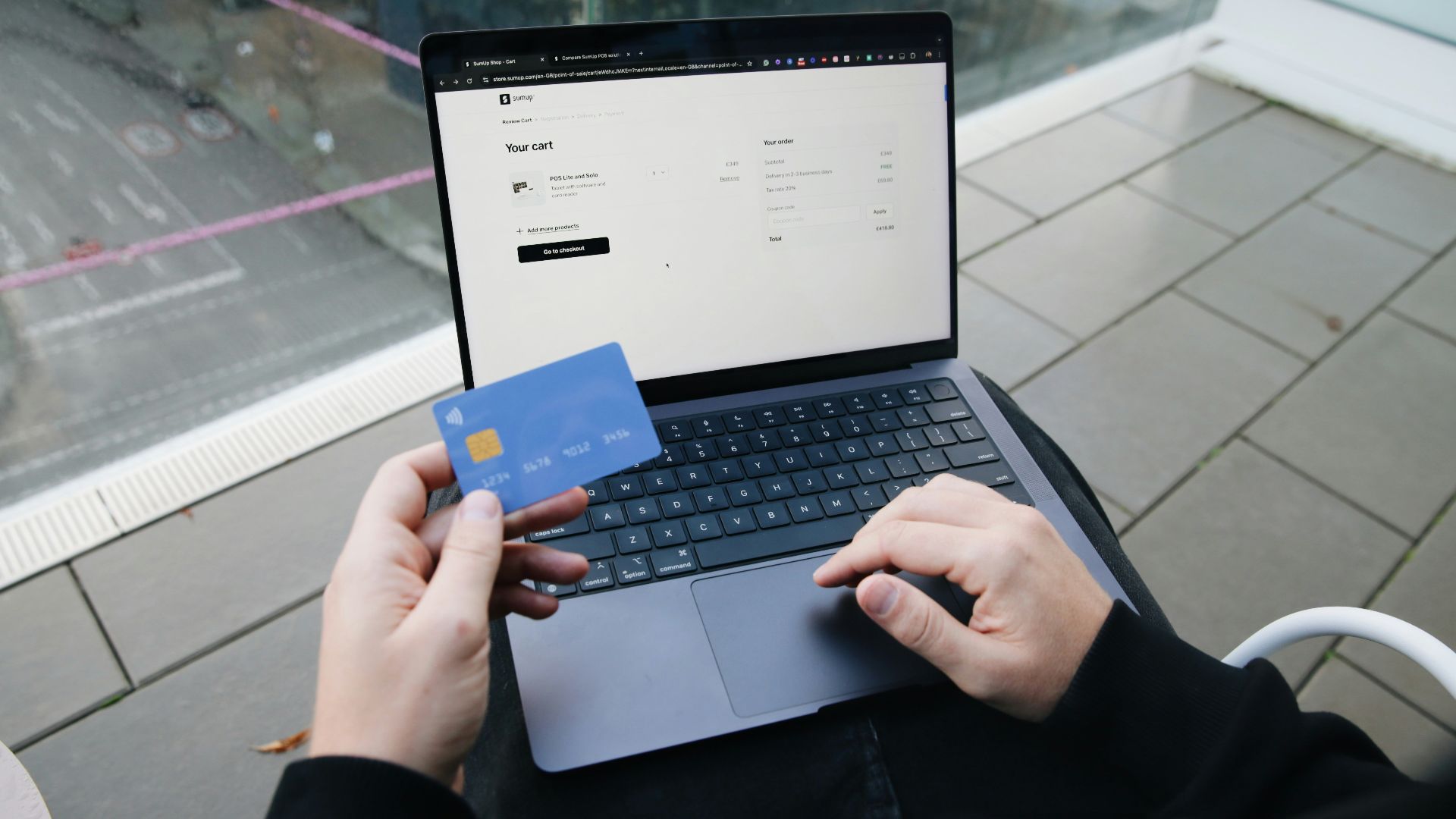 A person sitting in a chair with a laptop and a credit card