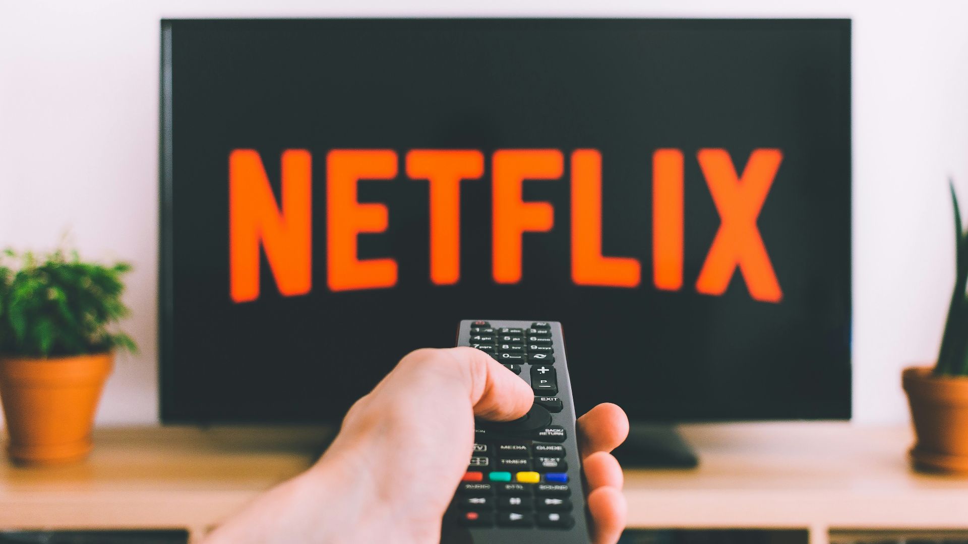 person holding remote pointing at TV