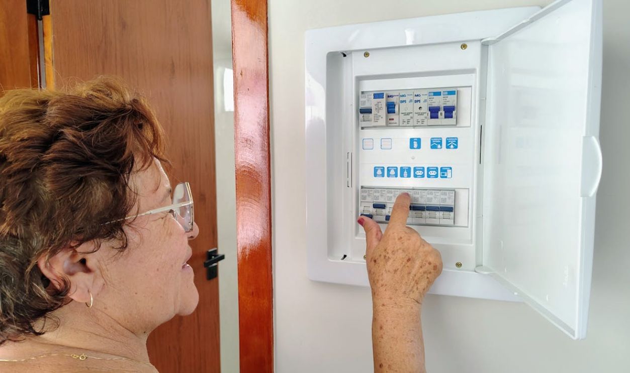 Senior Woman Adjusting Electrical Fuse Box