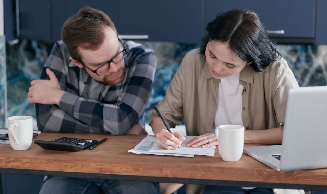 A Woman Filling Out a Form Beside a Man