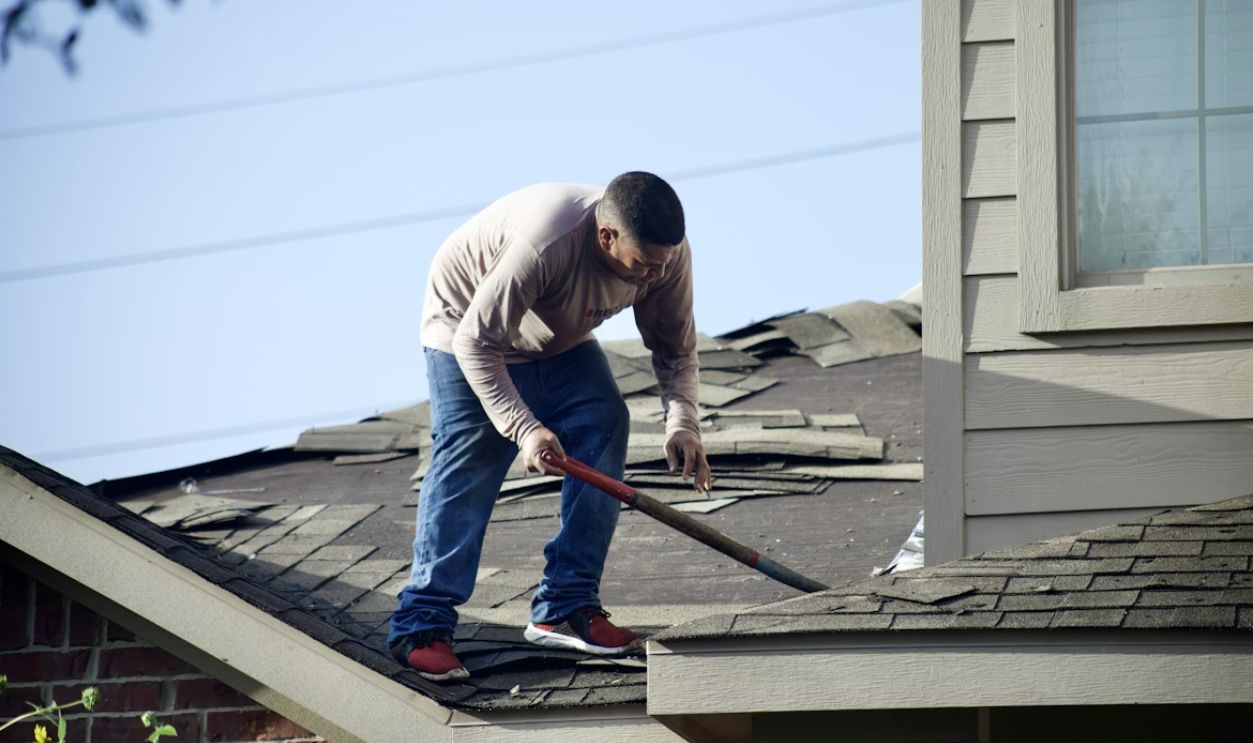 a man with a hammer on top of a roof