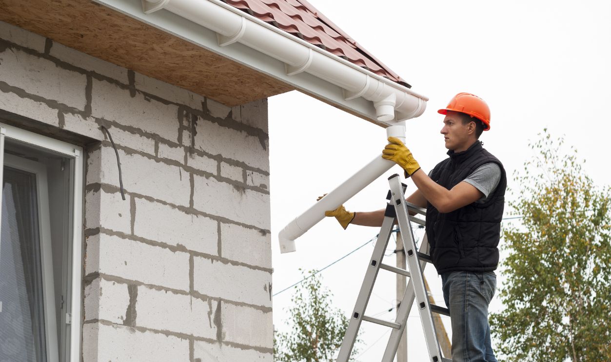 worker installs the gutter system on the roof