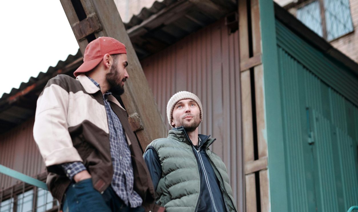 Men Leaning on Metal Railings while Having a Conversation