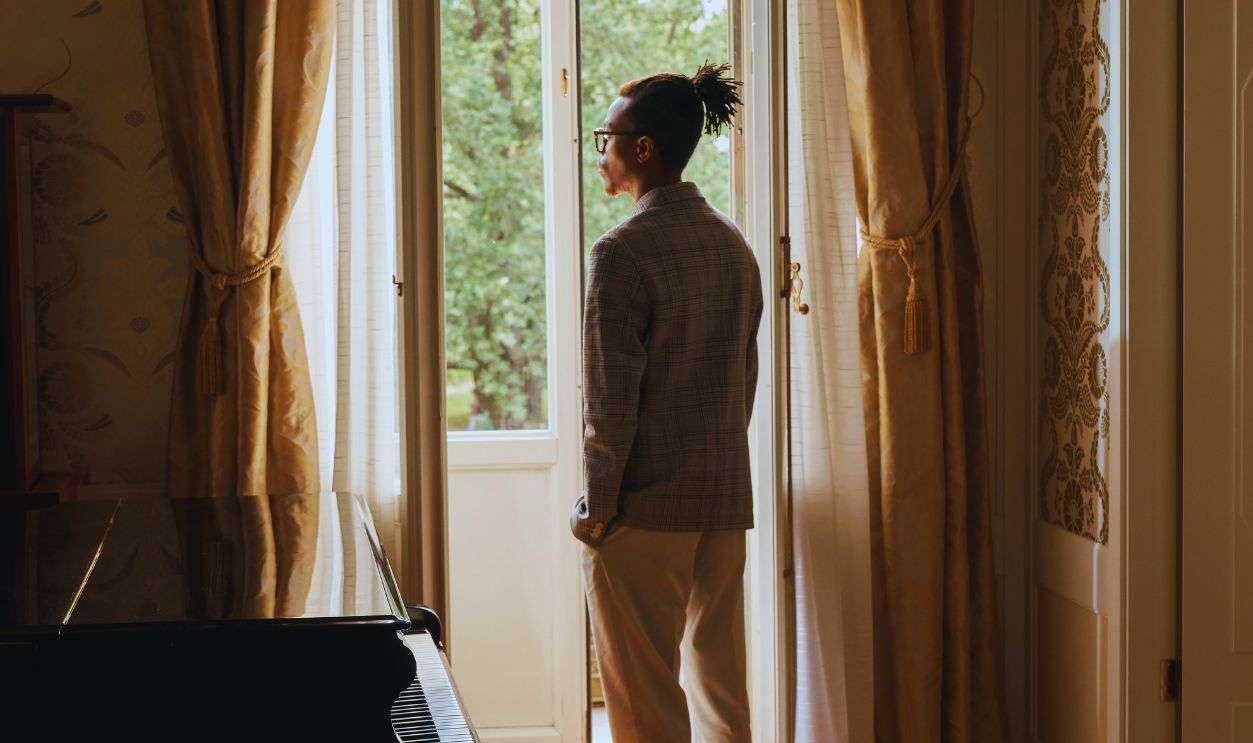 Rear View on Man Standing near Piano and Looking through Window