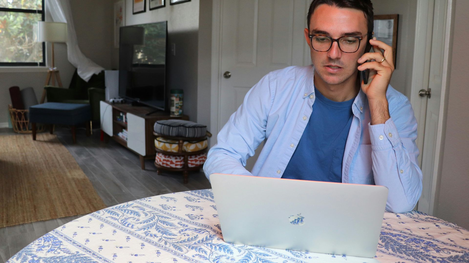 man in white dress shirt wearing eyeglasses sitting by the table using macbook