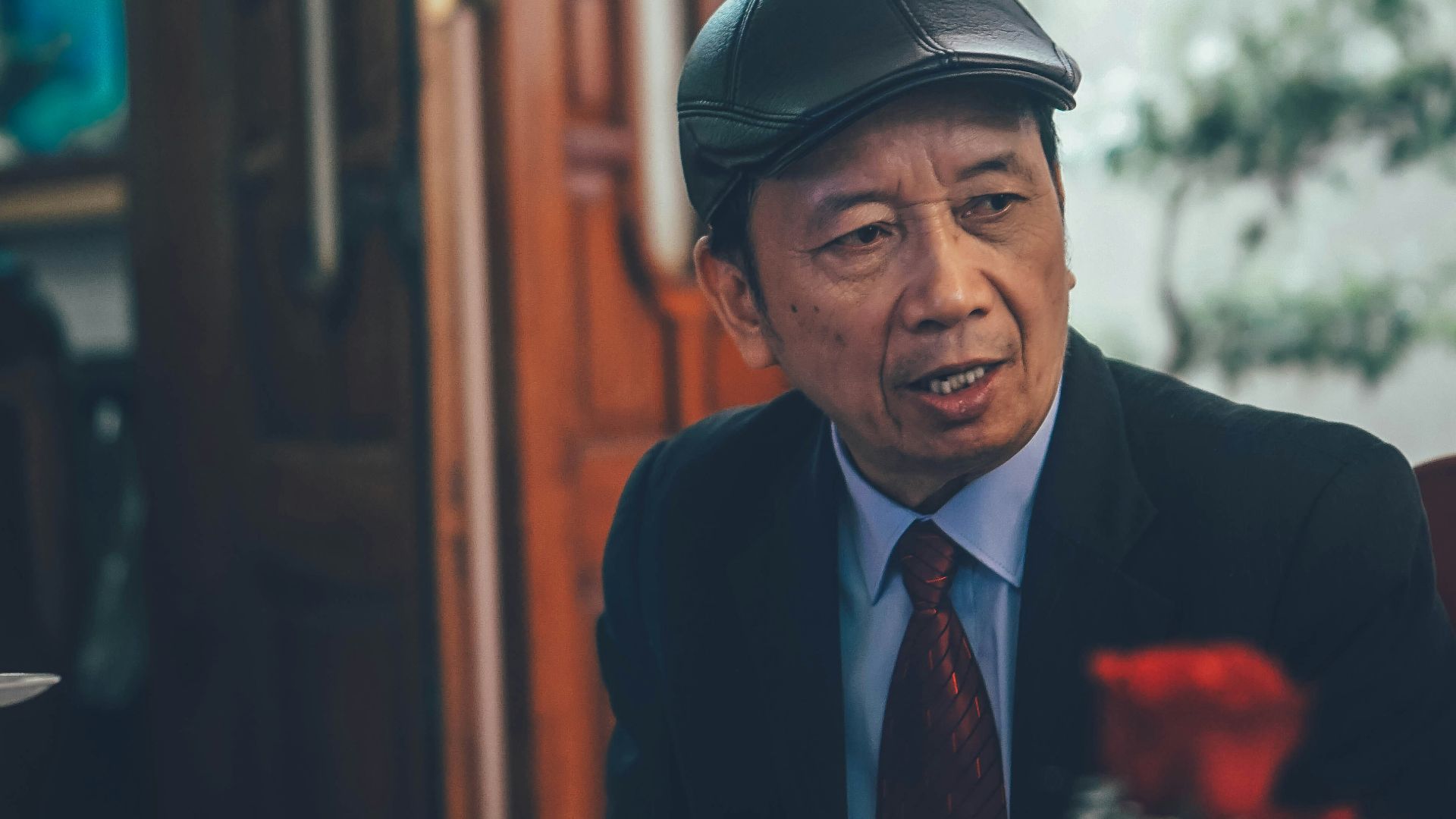 Elderly asian man wearing a hat and suit.