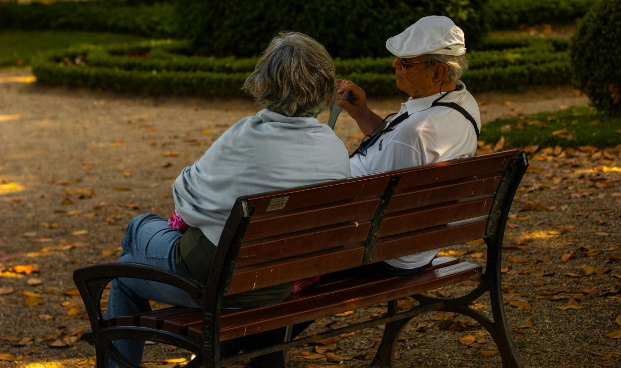 Elderly Couple Relaxing in Leafy Park on Bench