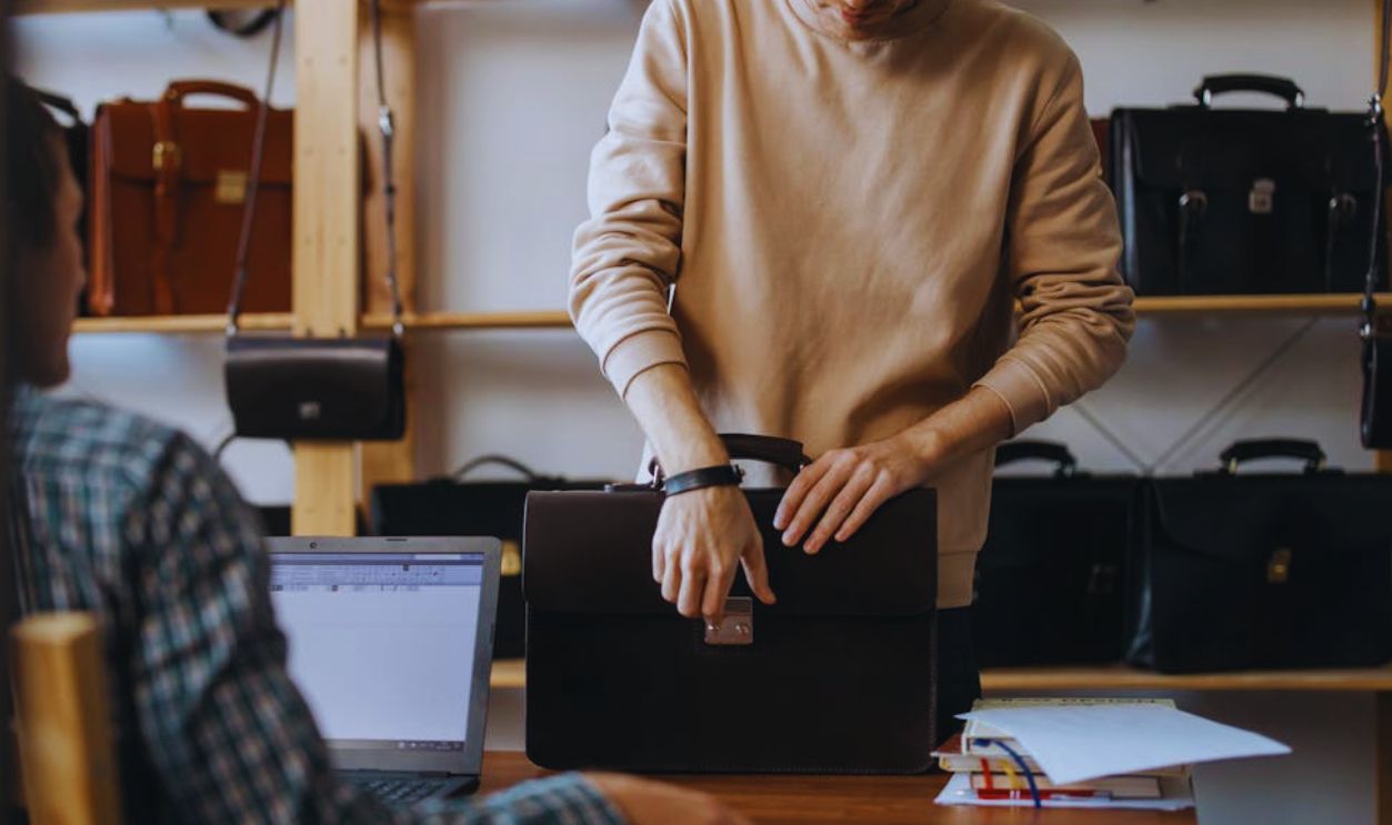 A Man in Brown Sweater Checking a Leather Bag