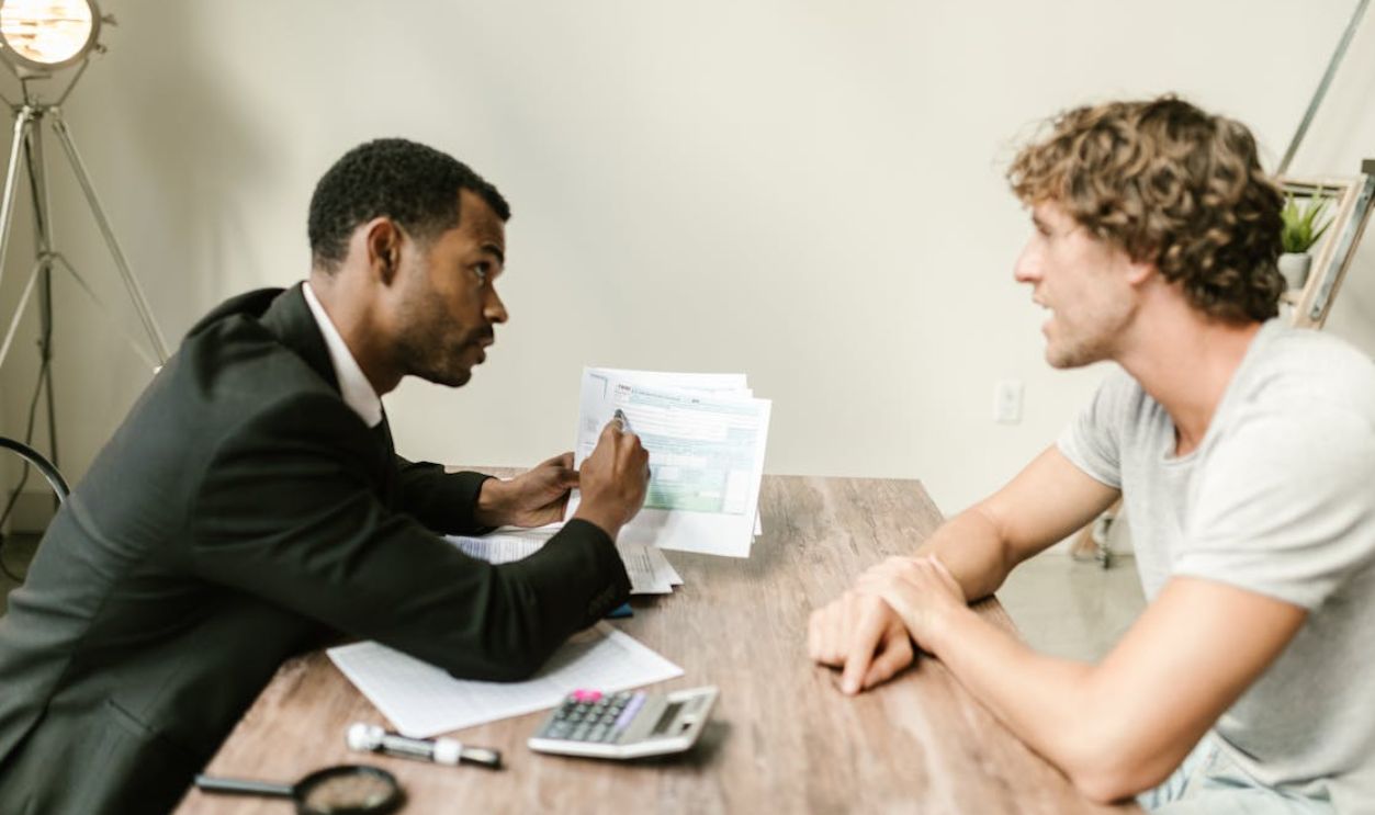 An Agent Showing Documents To His Client