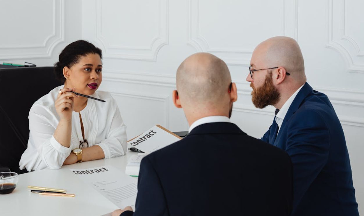 A Woman Talking to Men Holding Contracts