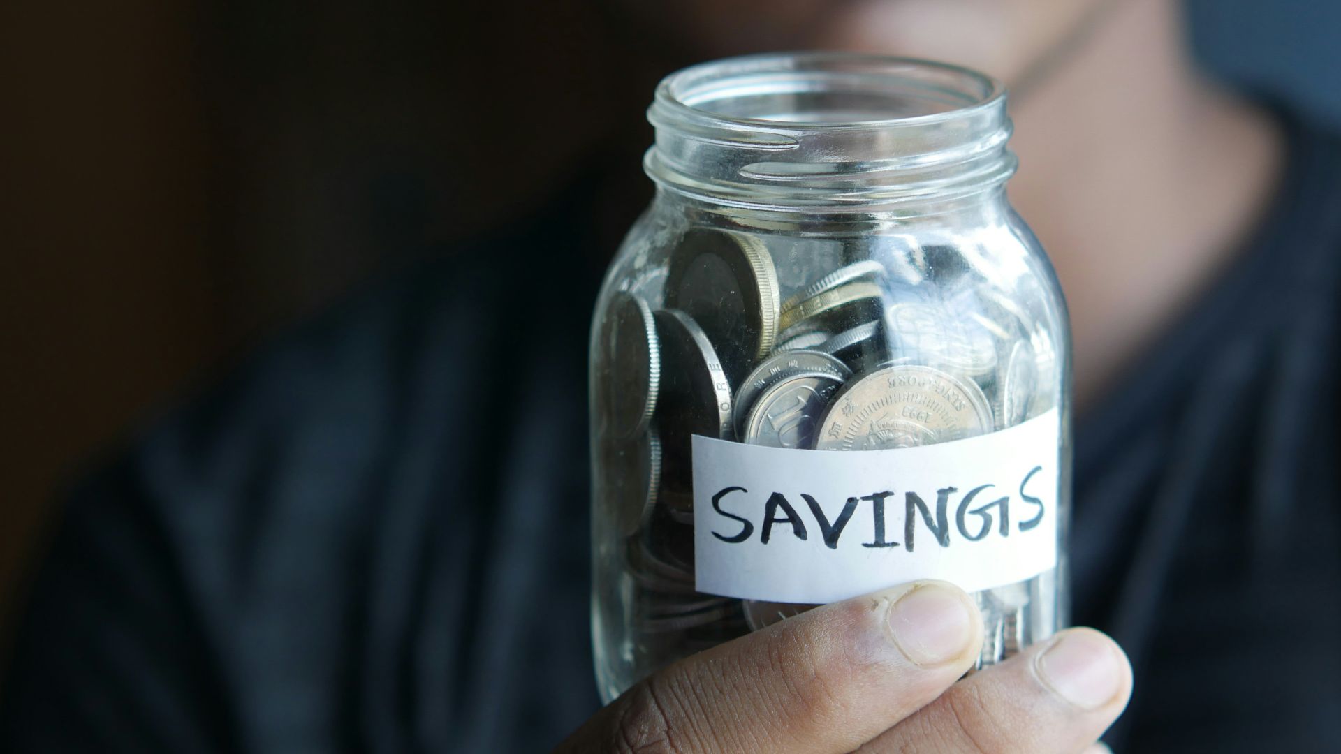 a man holding a jar with a savings label on it