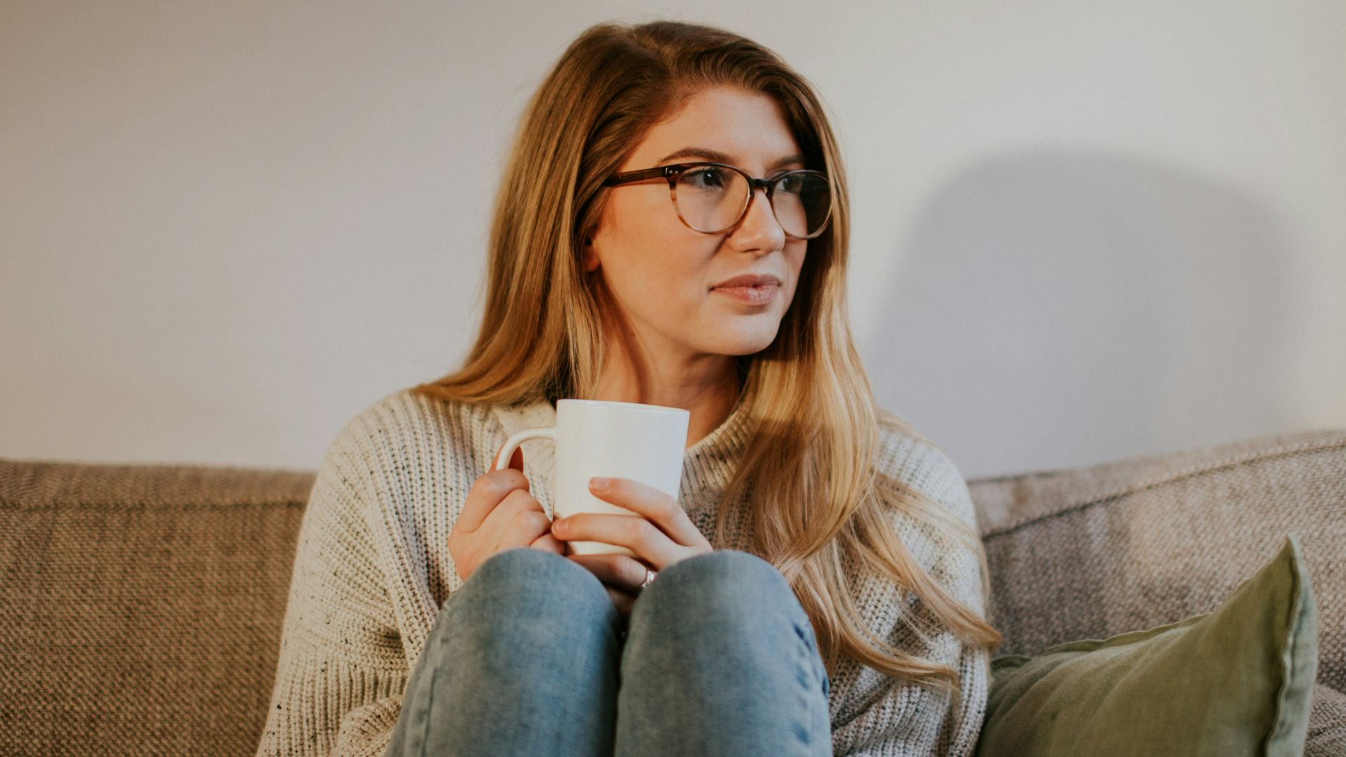 woman in blue denim jeans sitting on gray sofa