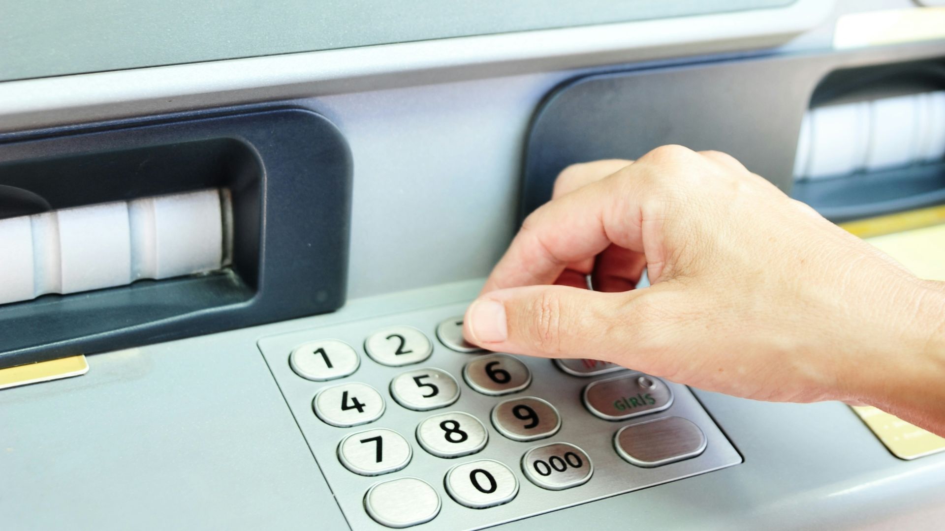 Hand using keypad on an atm machine.