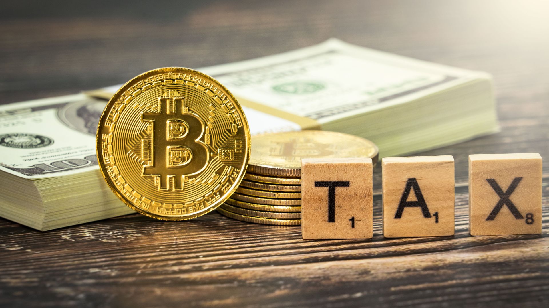 Crypto tax concept image that shows a Bitcoin cryptocurrency medallion alongside some cash and some Scrabble titles spelling out the word 'tax'. This image is available for you to use under the Attribution Creative Commons licence, though you must provide attribution in the form of a link to www.bybit.com