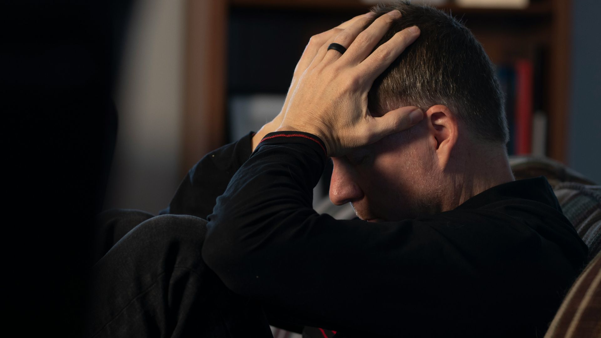a man sitting on a couch holding his head in his hands