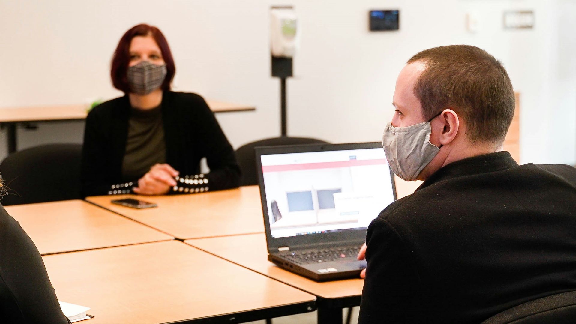 a group of people sitting around a table wearing face masks