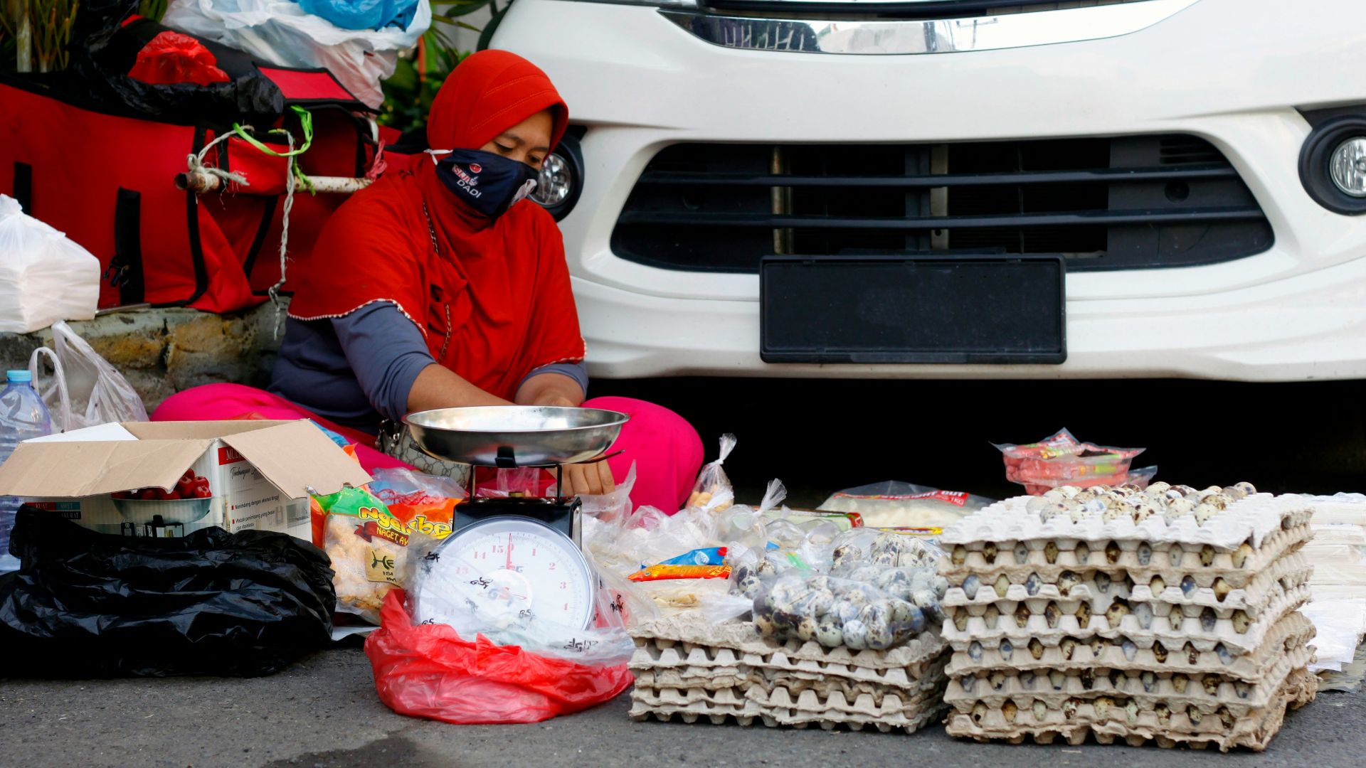 woman in blue jacket sitting on floor beside white car