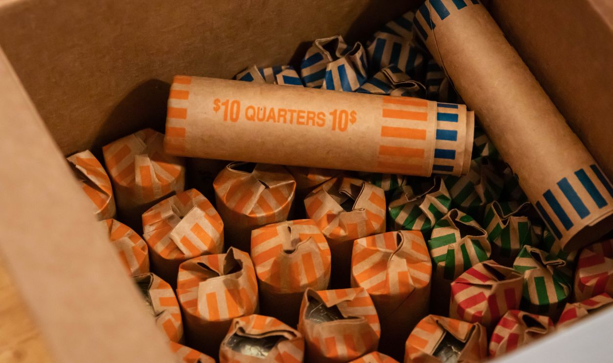 American currency coins rolled up into coin rollers. Savings being prepared for bank deposit. Quarters, dimes, nickles and pennies. Dollars.