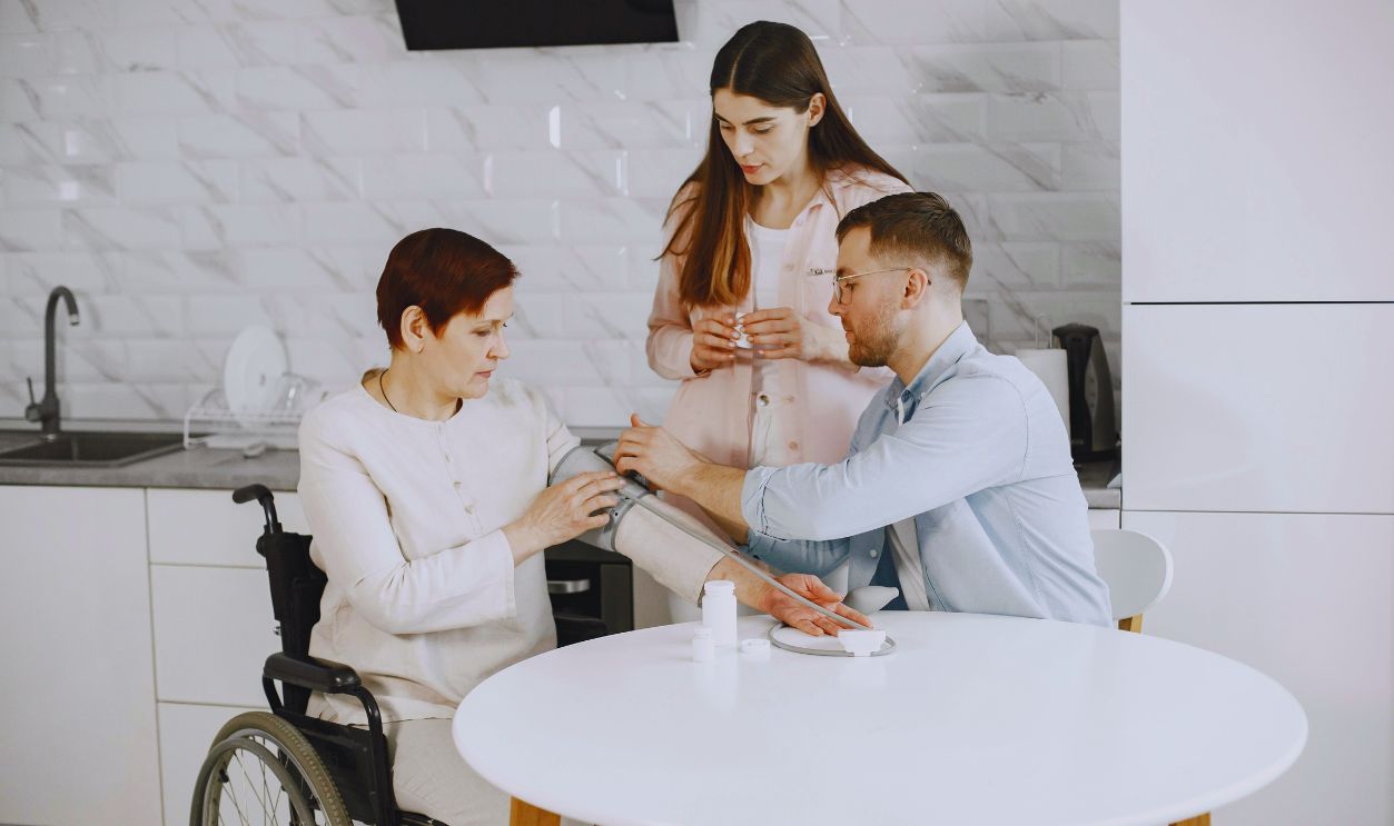 A Man Monitoring the Blood Pressure of the Woman Sitting on the Wheelchair Using Sphygmomanometer