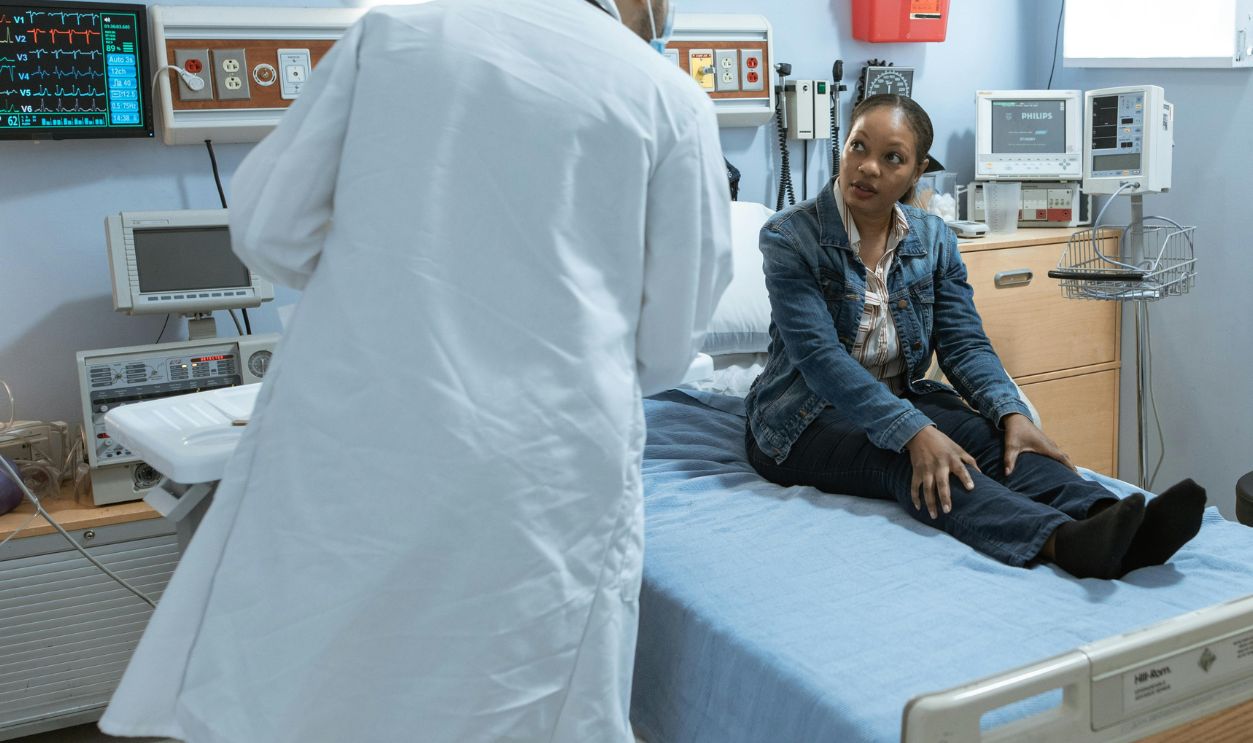 Doctor Talking to a Patient Sitting on Bed