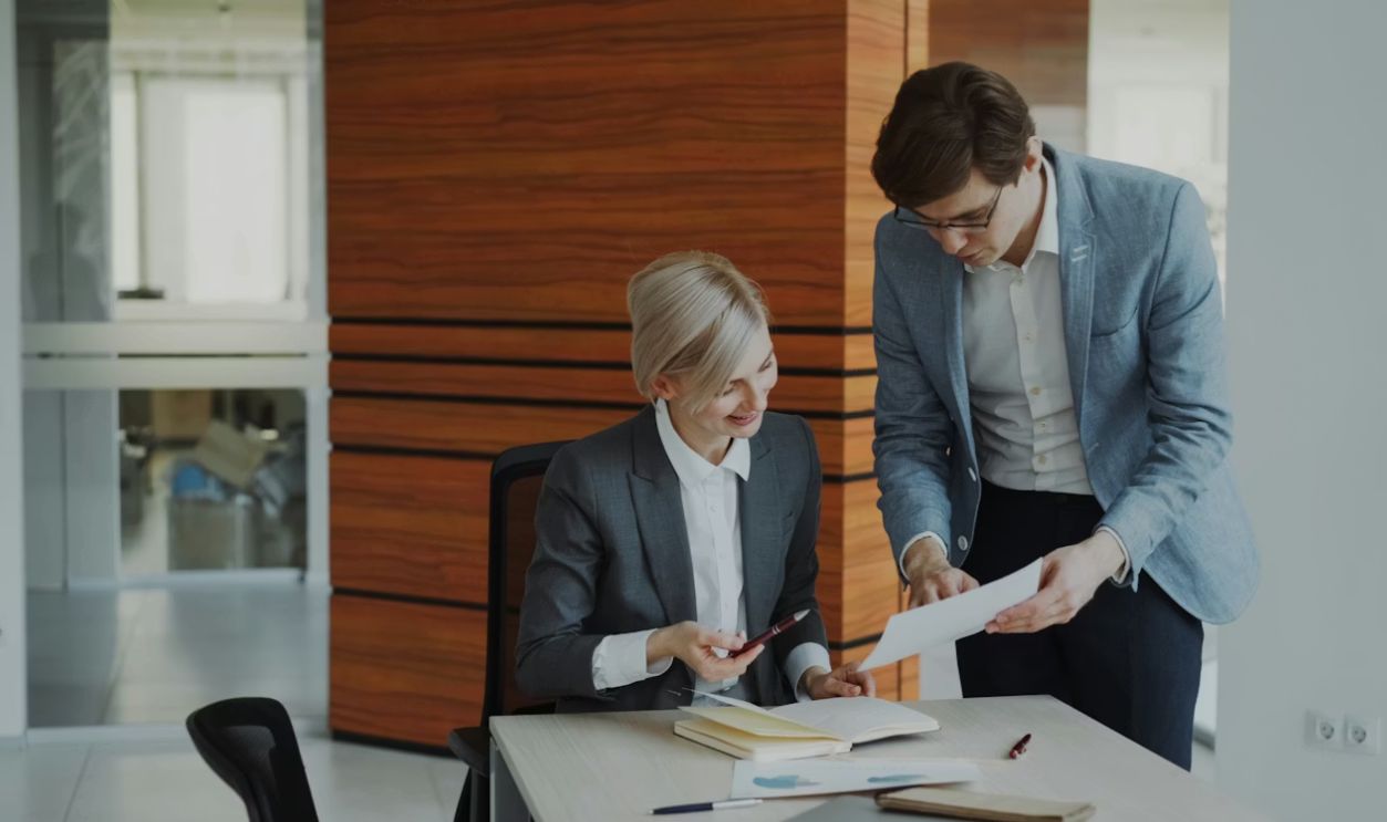 Two colleagues discussing documents at an office desk