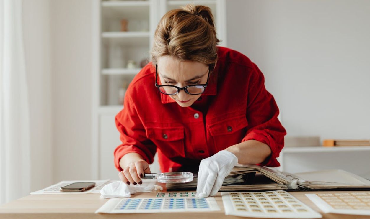 A Woman Using a Magnifying Glass on Postage Stamps