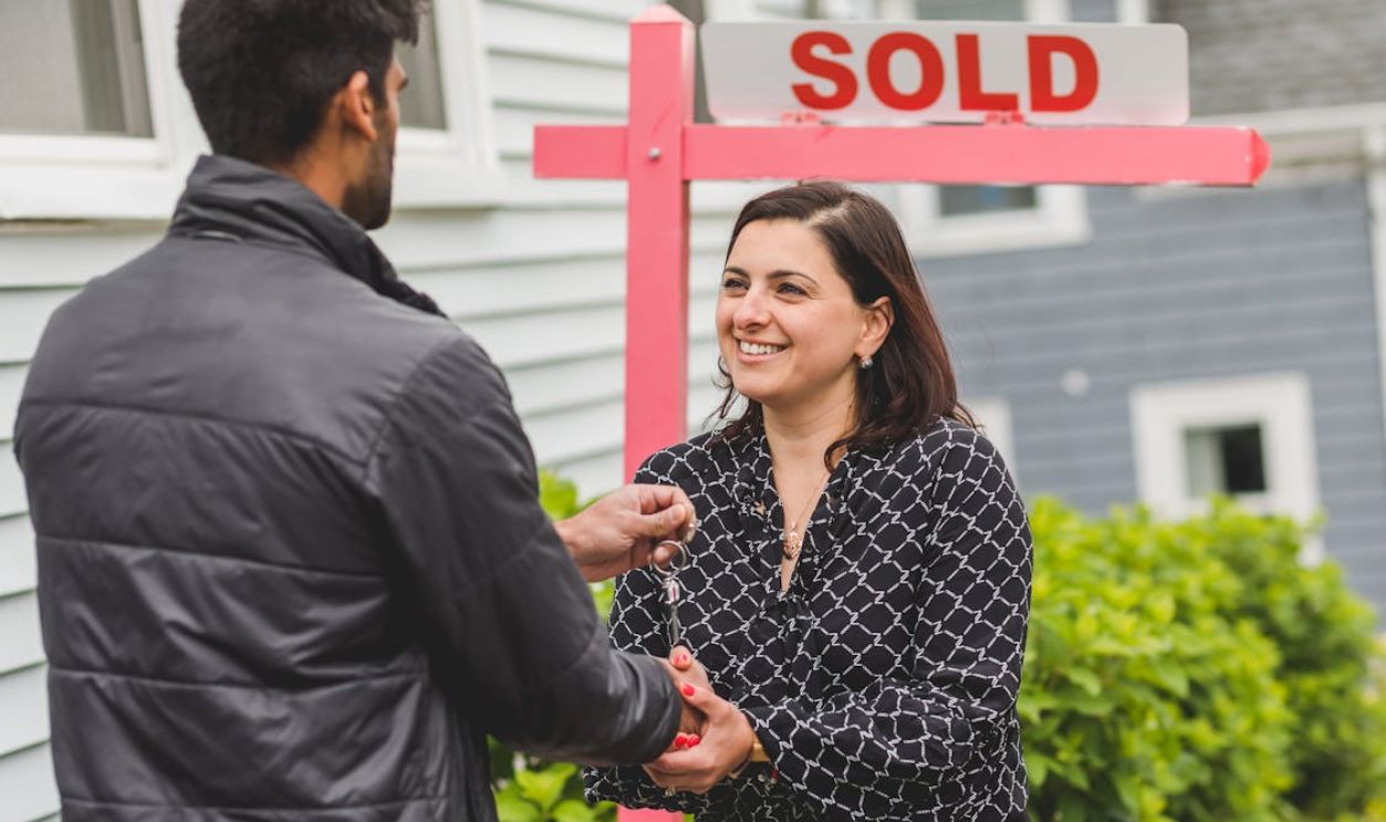 A Man Handing the Key to the Woman while Shaking their Hands