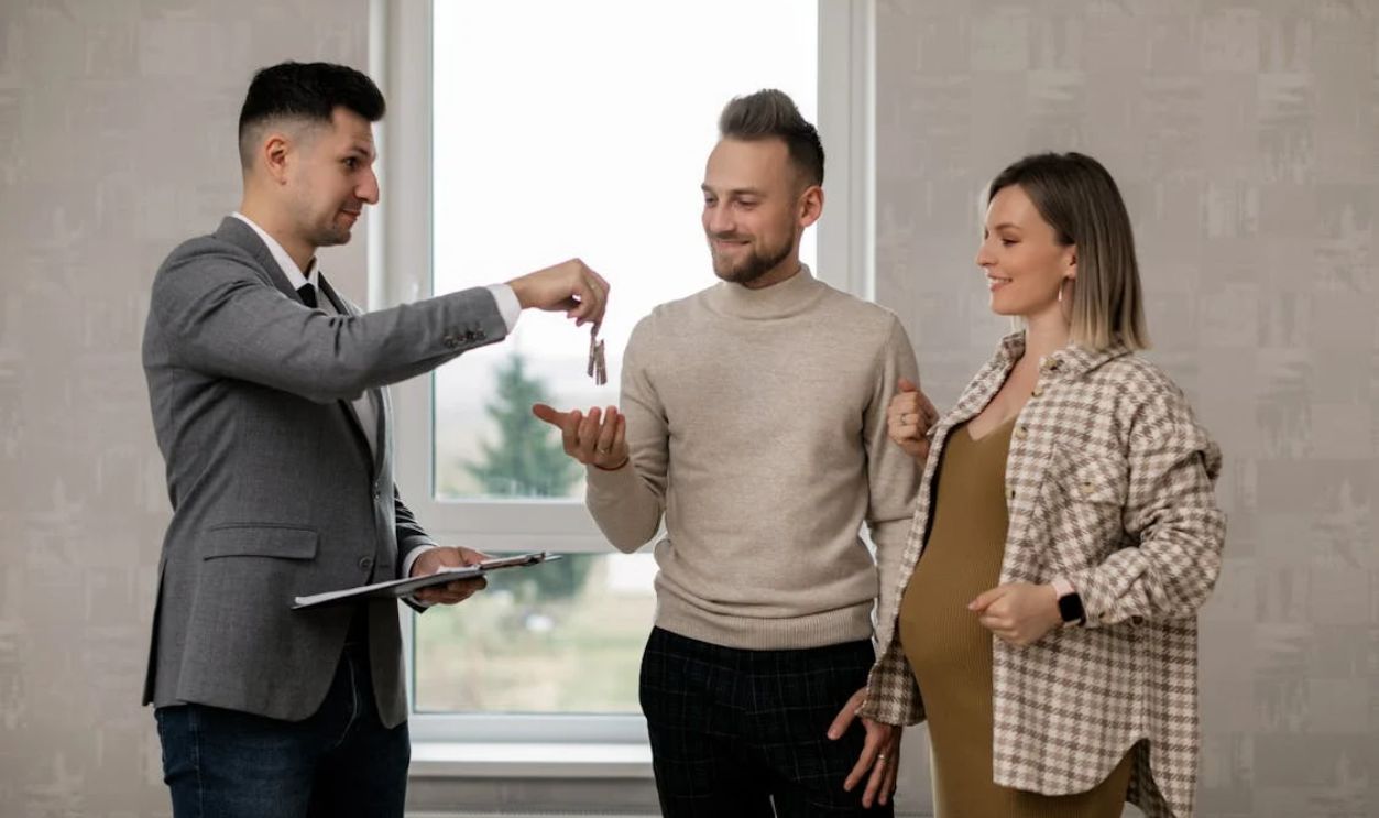 A Real Estate Agent Handing the Key to the New Homeowners