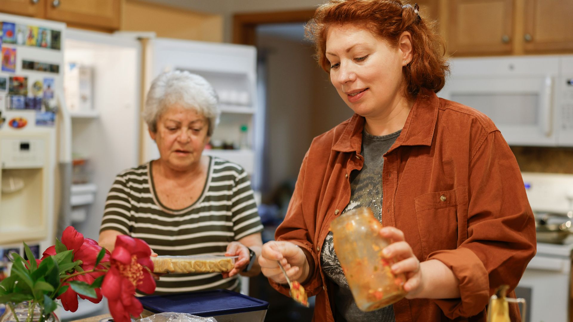 Two women preparing food in a kitchen.