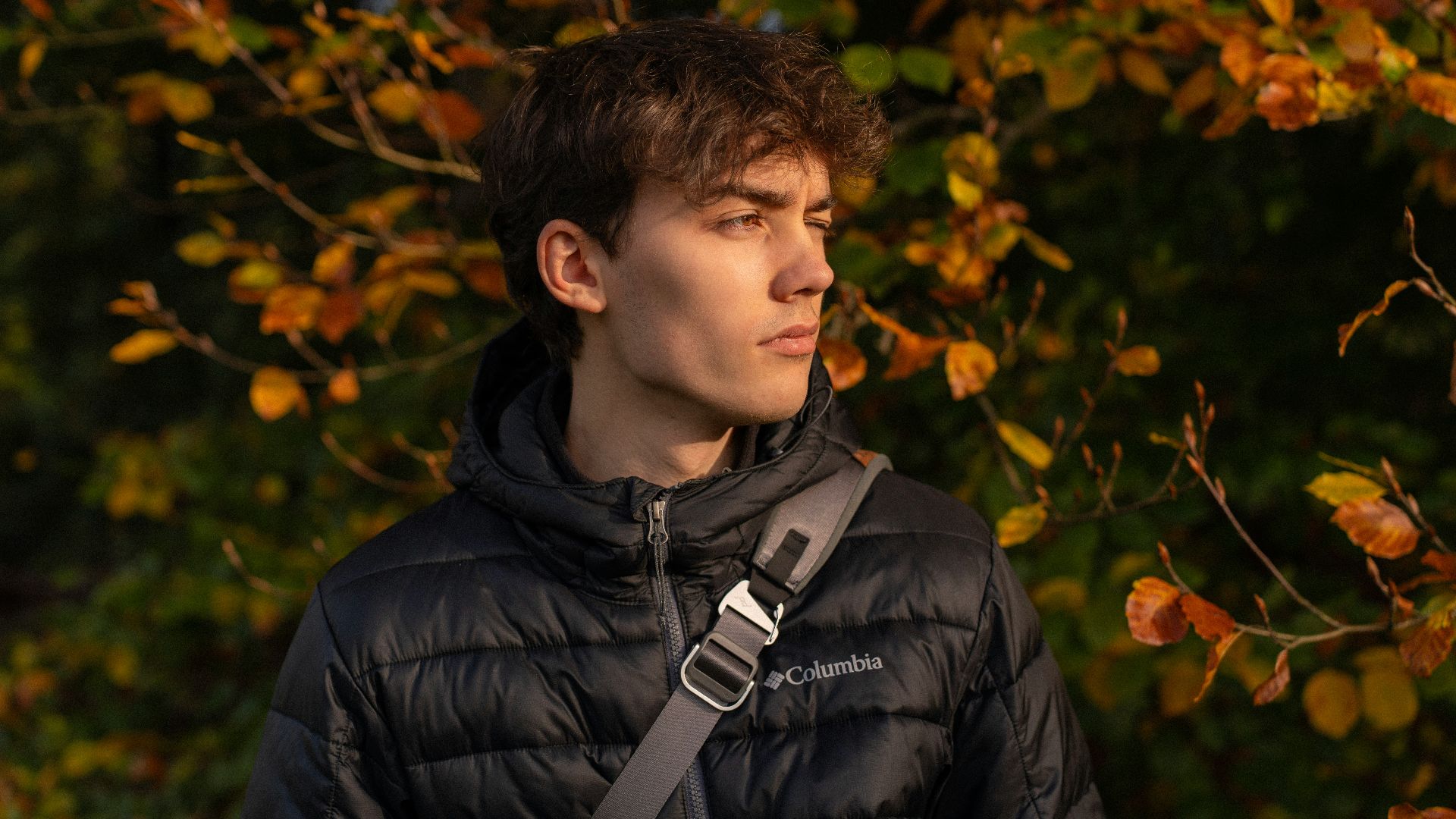 Young man in a puffer jacket with autumn leaves